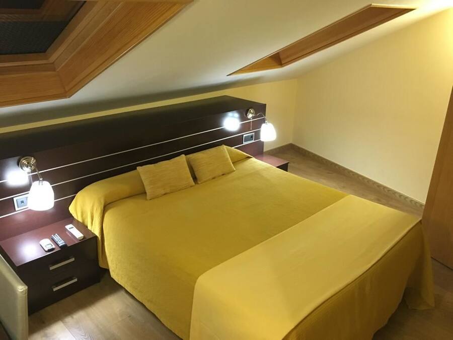 Ein Schlafzimmer mit einem Bett, Nachttischen und einem Kopfteil mit Beleuchtung.