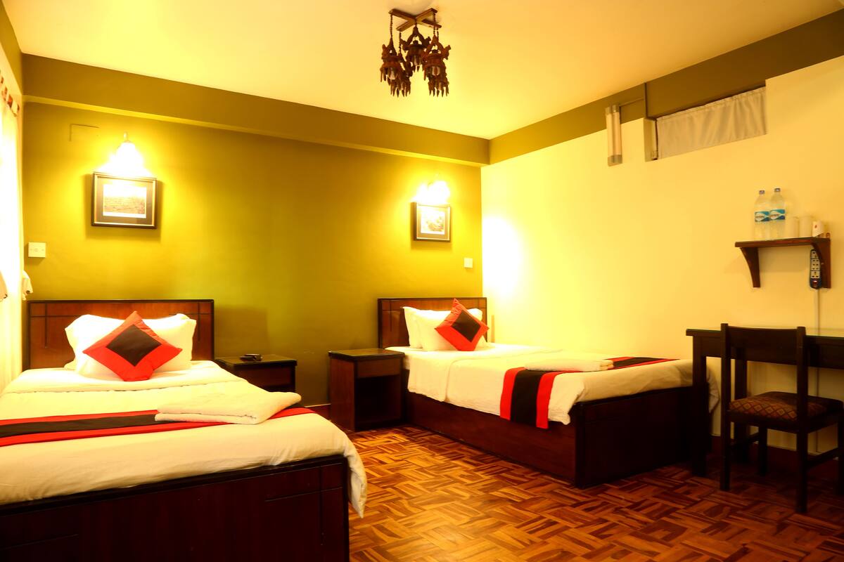 A hotel room with two beds, wooden flooring, and a chair.