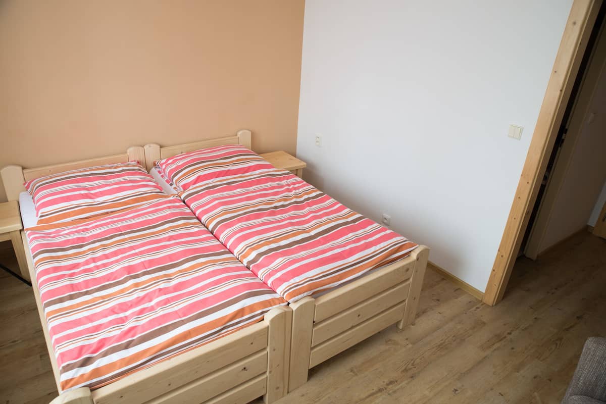 Una cama individual con colcha a rayas en una habitación con suelo de madera y pared lisa.