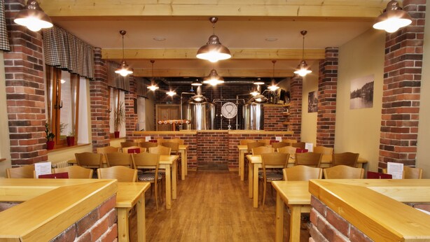 Een restaurant met bakstenen muren, houten tafels en hangende lampen.