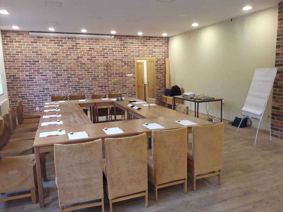 A conference room with a long table, chairs, a whiteboard, and a brick wall.