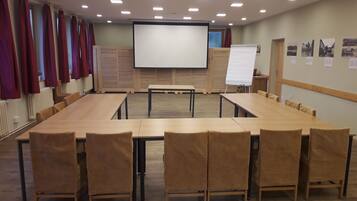 A conference room with a long table, chairs, a projector screen, and a whiteboard.
