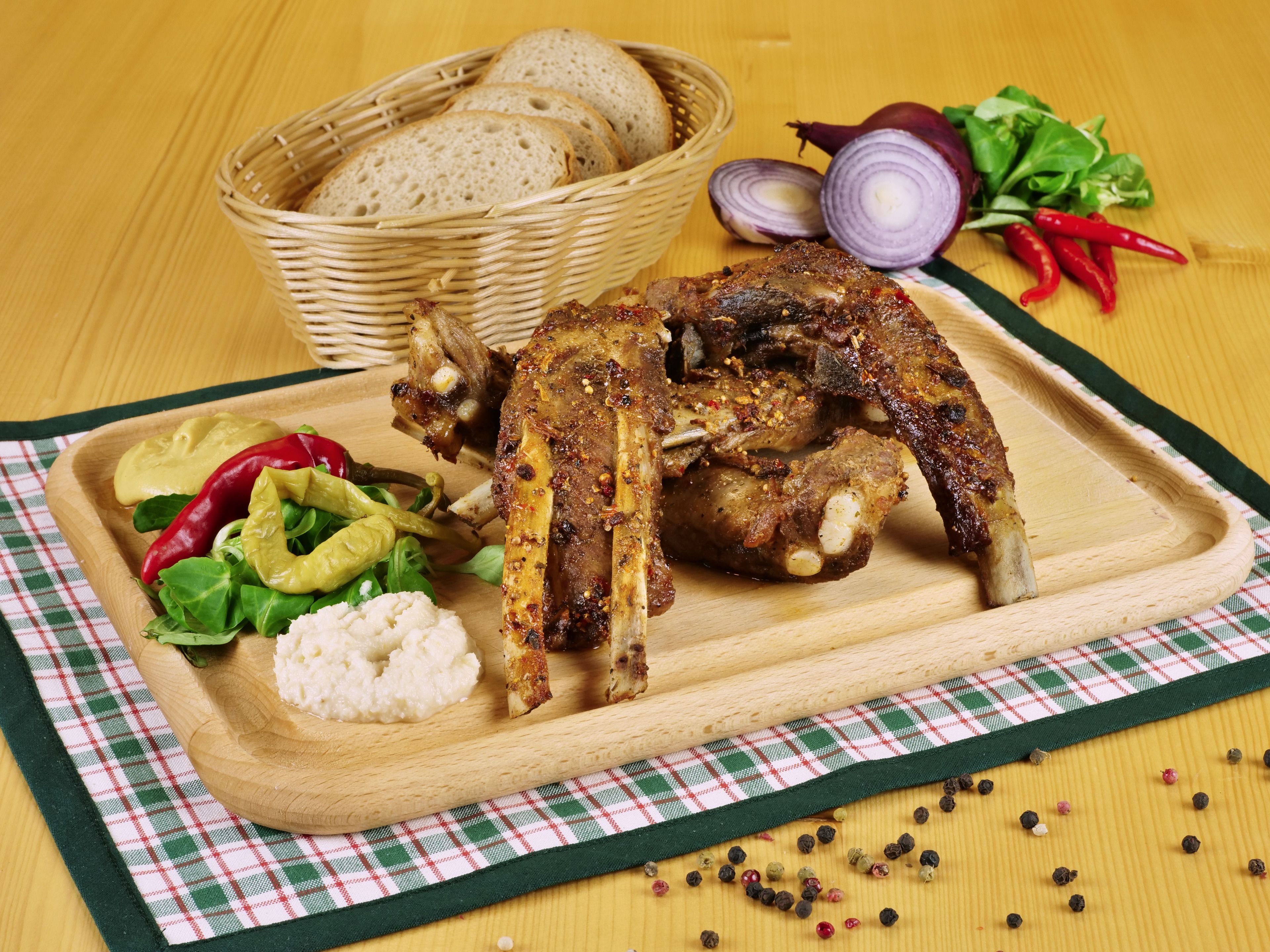 A wooden cutting board with roasted chicken, bread, and salad.