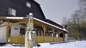 Een hotel met een houten gevel, een overdekte veranda en een bord waarop staat dat het het Radesin Hotel is.