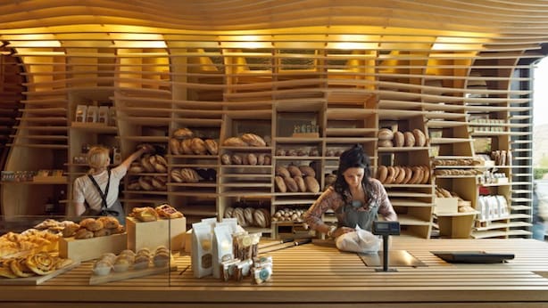 A bakery with shelves of baked goods and two staff members. - Class, Style and Location in Carlton (Carlton)