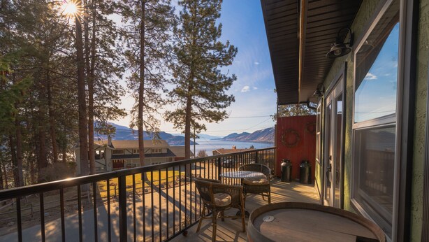 A balcony with a view of mountains, a wooden barrel, and wicker furniture.