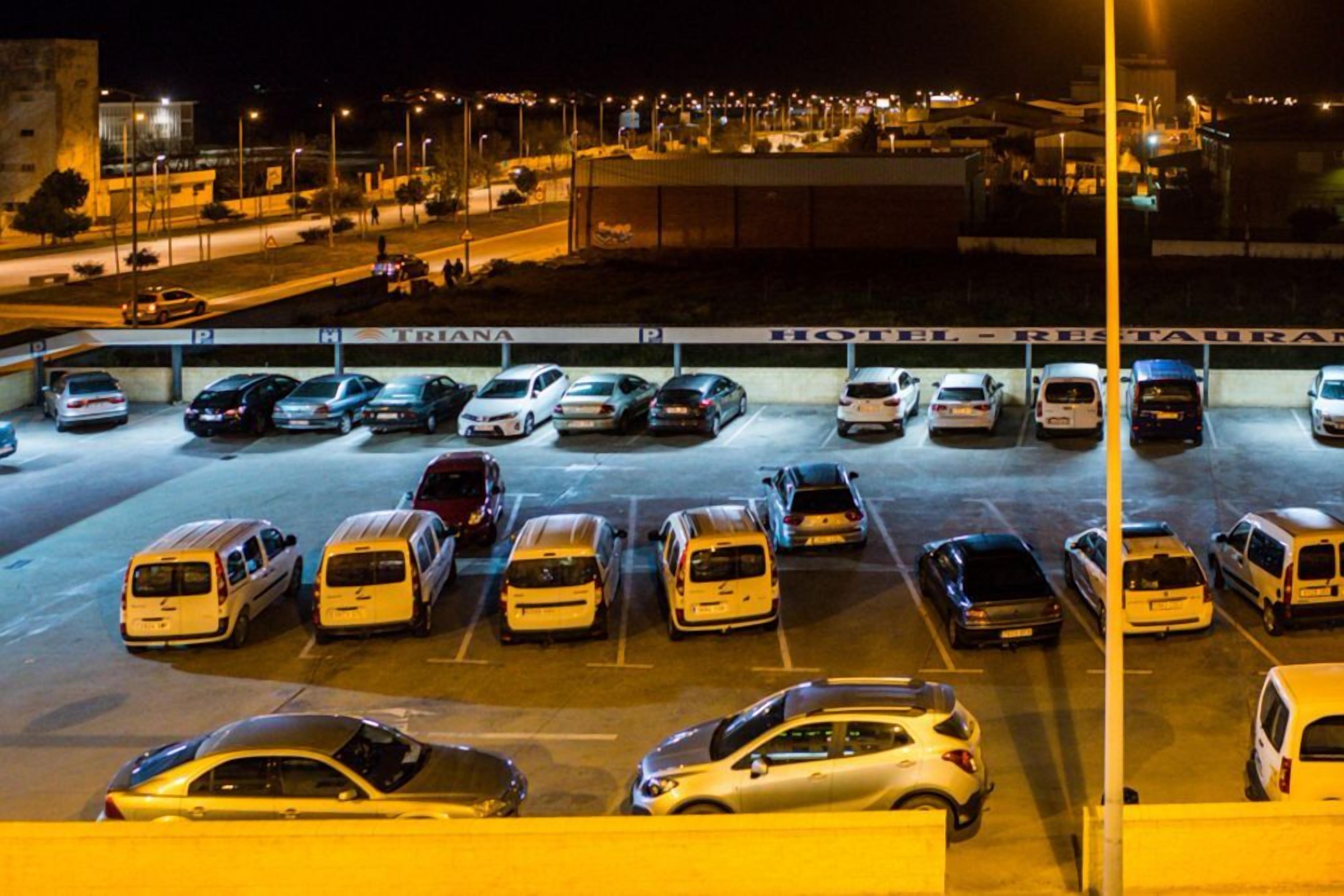 A parking lot with multiple cars and vans, a hotel sign, and a building in the background.