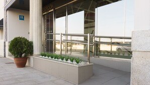 Entrada de hotel con mostrador de recepción, una planta en maceta y un jarrón con plantas pequeñas.