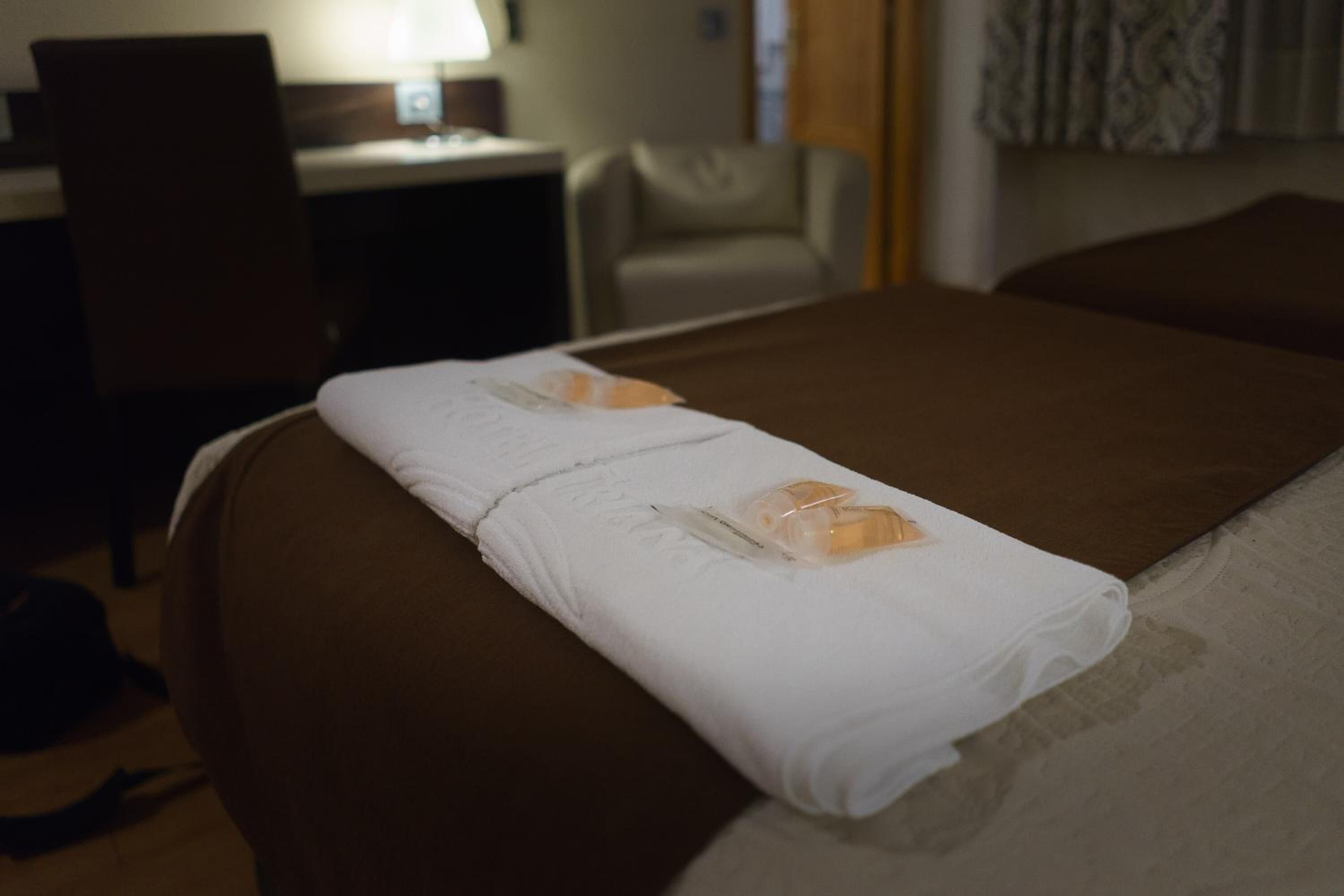 A hotel room with a bed, a desk, and a chair.