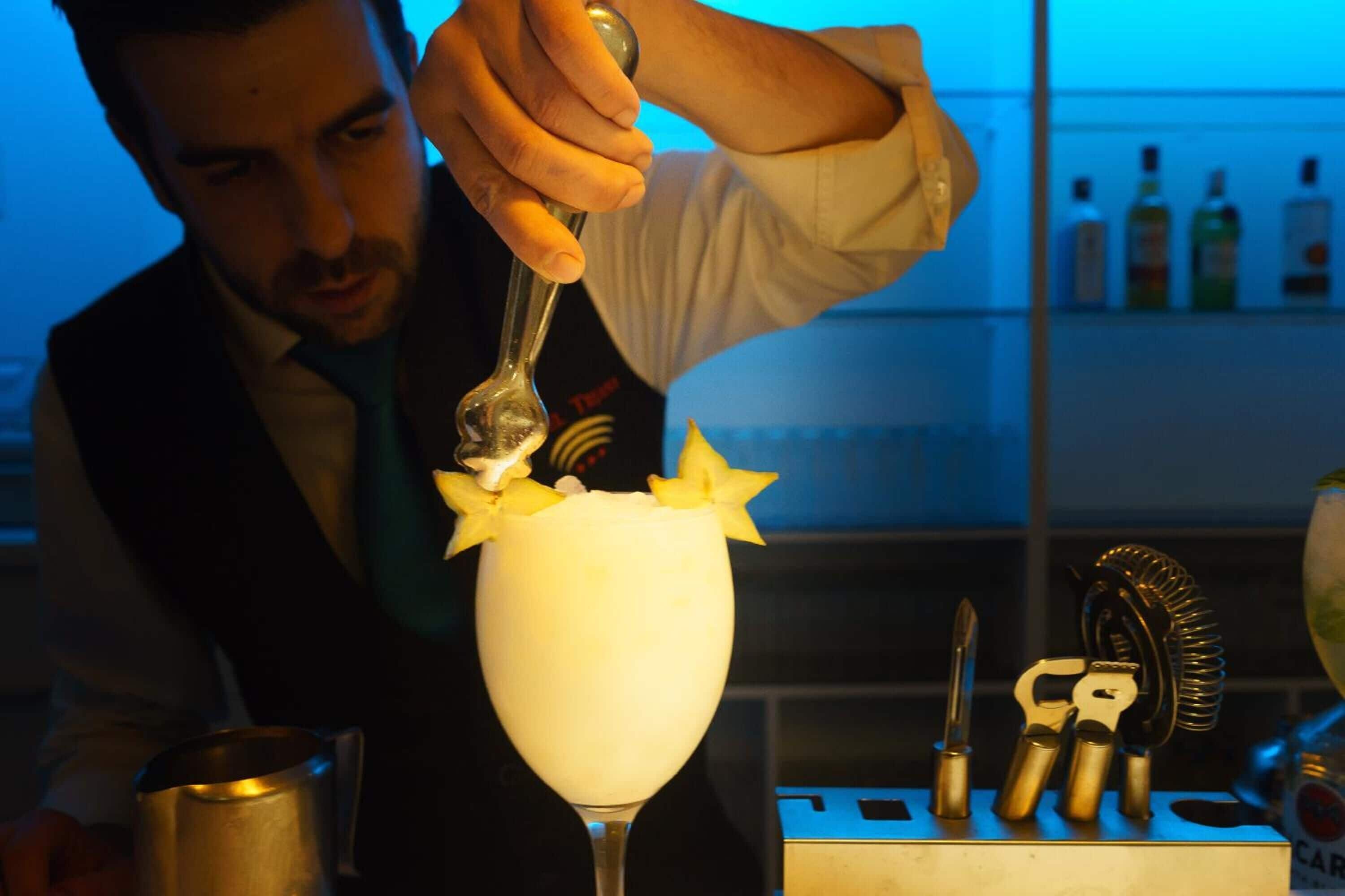 A bartender preparing a cocktail with a spoon.