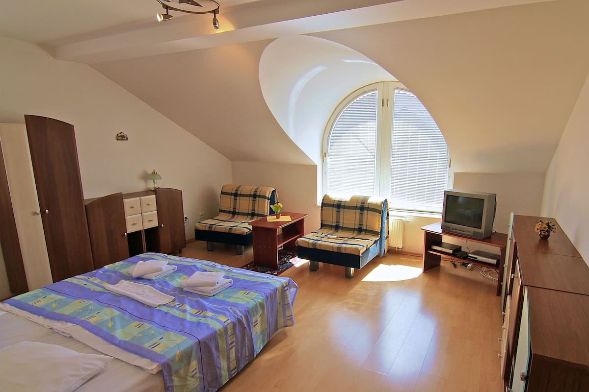 A bedroom with a bed, two chairs, a TV, and a desk.
