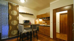 A modern kitchen with wooden cabinets, a microwave, and a dining area with striped chairs.