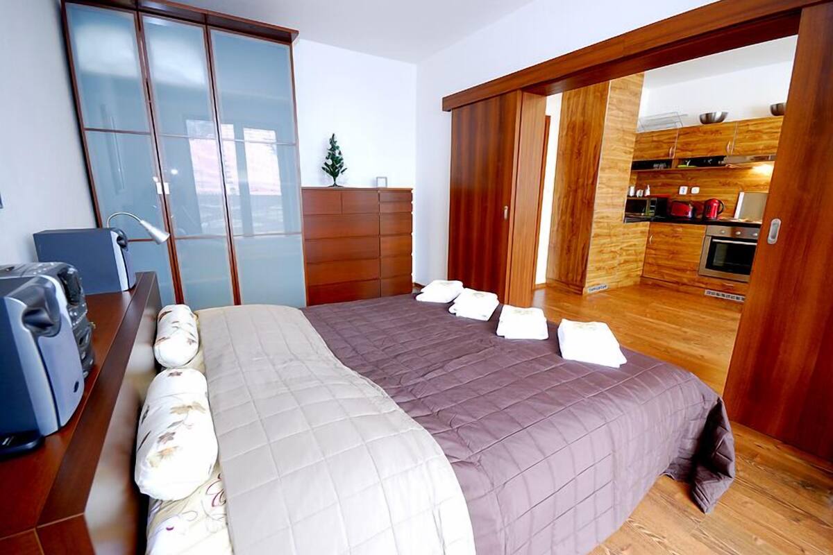 Una camera da letto con un letto grande, una scrivania con un computer e una porta scorrevole che dà su una cucina.