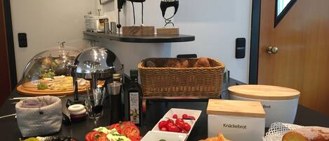 Un bufé de desayuno con diversos alimentos, como pan, pastelería y una selección de quesos y frutas.