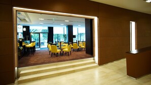 Un interior moderno con una escalera que lleva a un comedor con sillas y mesas amarillas.