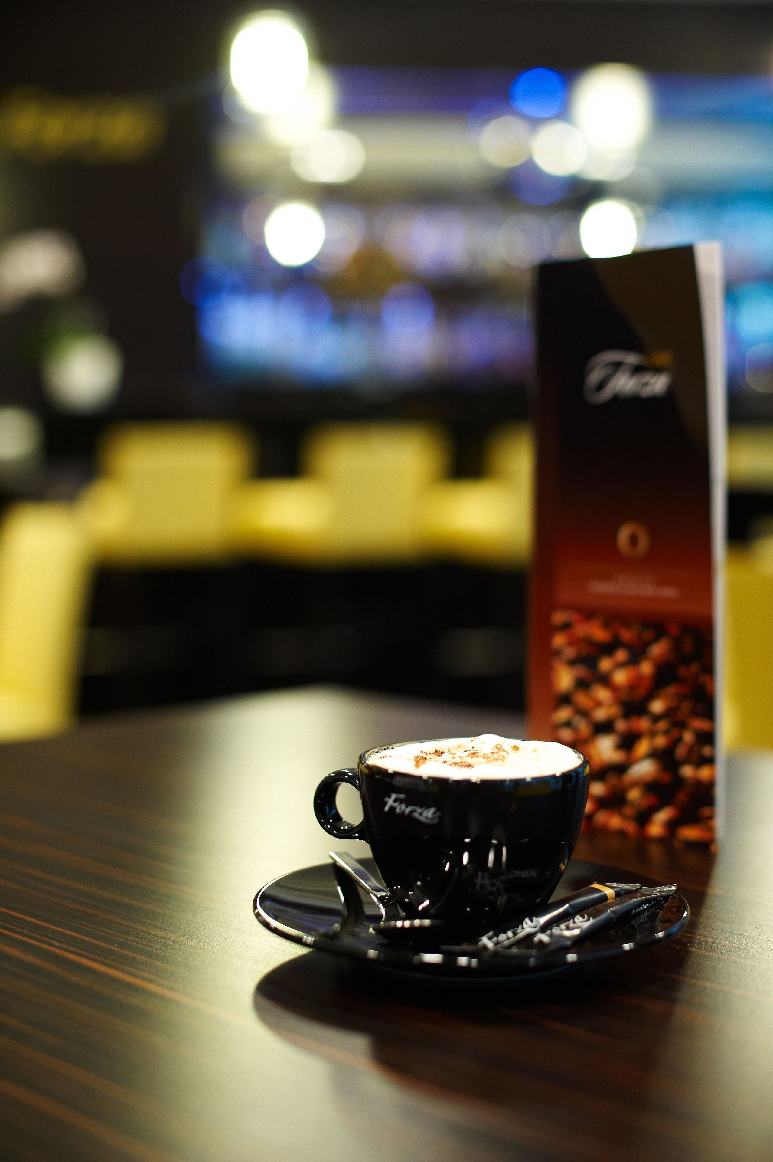 A cup of coffee on a saucer with a menu stand in the background.