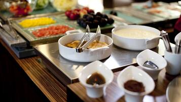 A buffet with various food items including fruits, vegetables, and sauces.