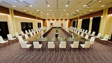 A conference room with a long table, white chairs, and a carpeted floor.