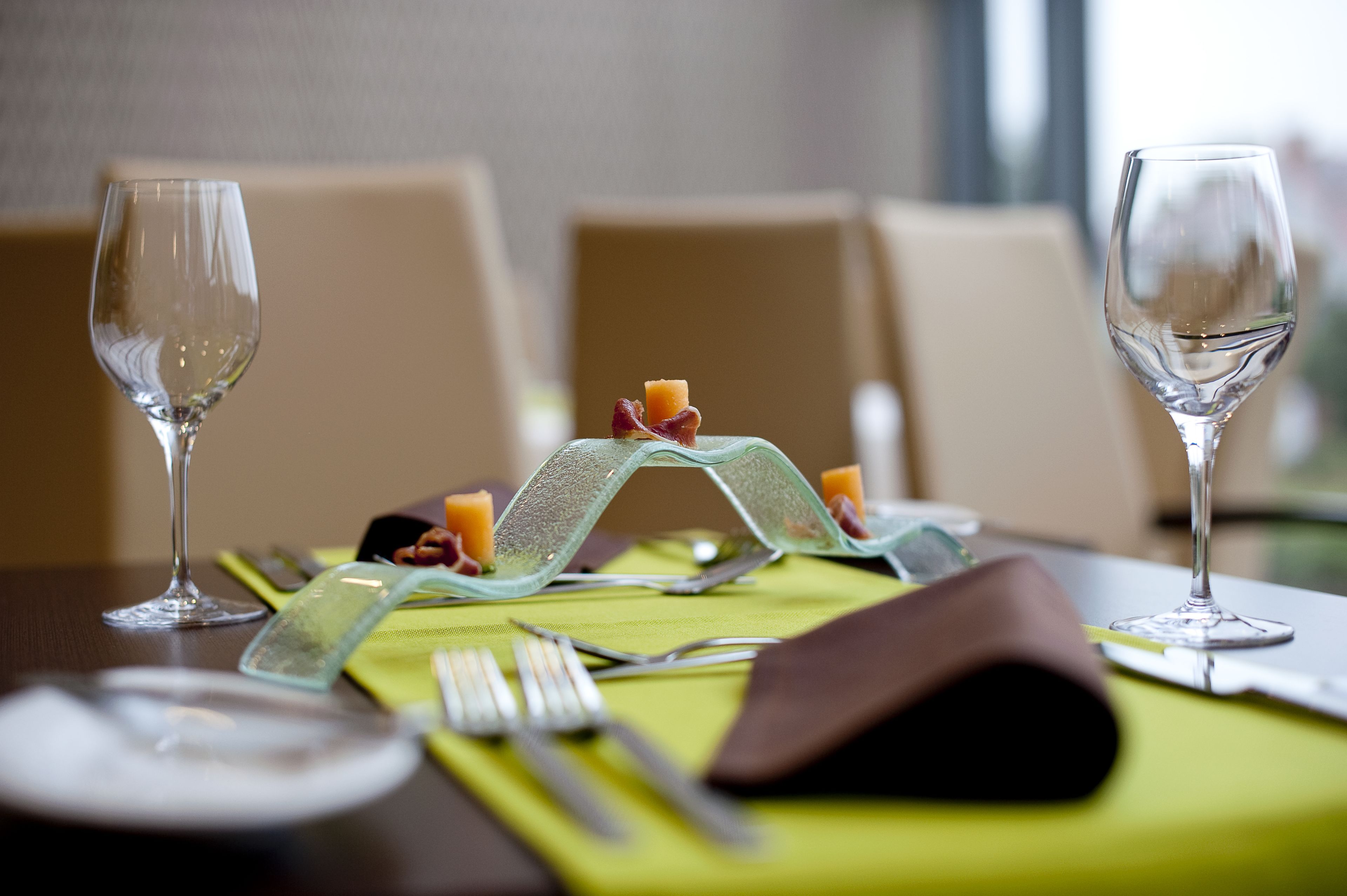 Une table à manger dressée avec de la vaisselle transparente, une serviette verte et un centre de table décoratif.