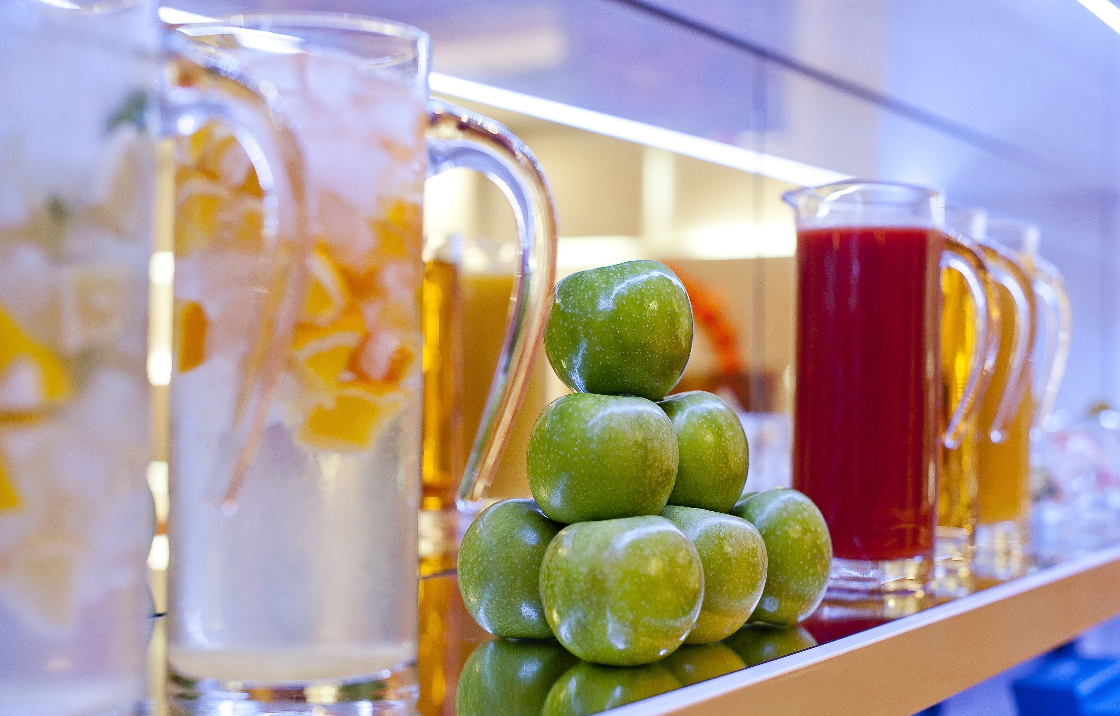 A beverage display with various drinks and a decorative stack of green apples.