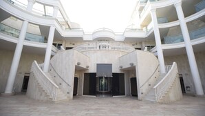 A spacious atrium with a central staircase, multiple balconies, and a modern architectural design. - City Resort Palmore (Eilat)