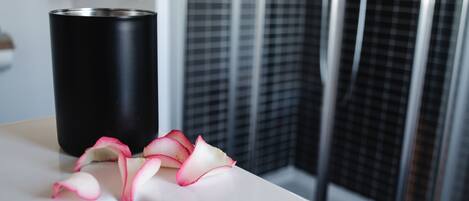 A black cylindrical object on a white surface with rose petals beside it.