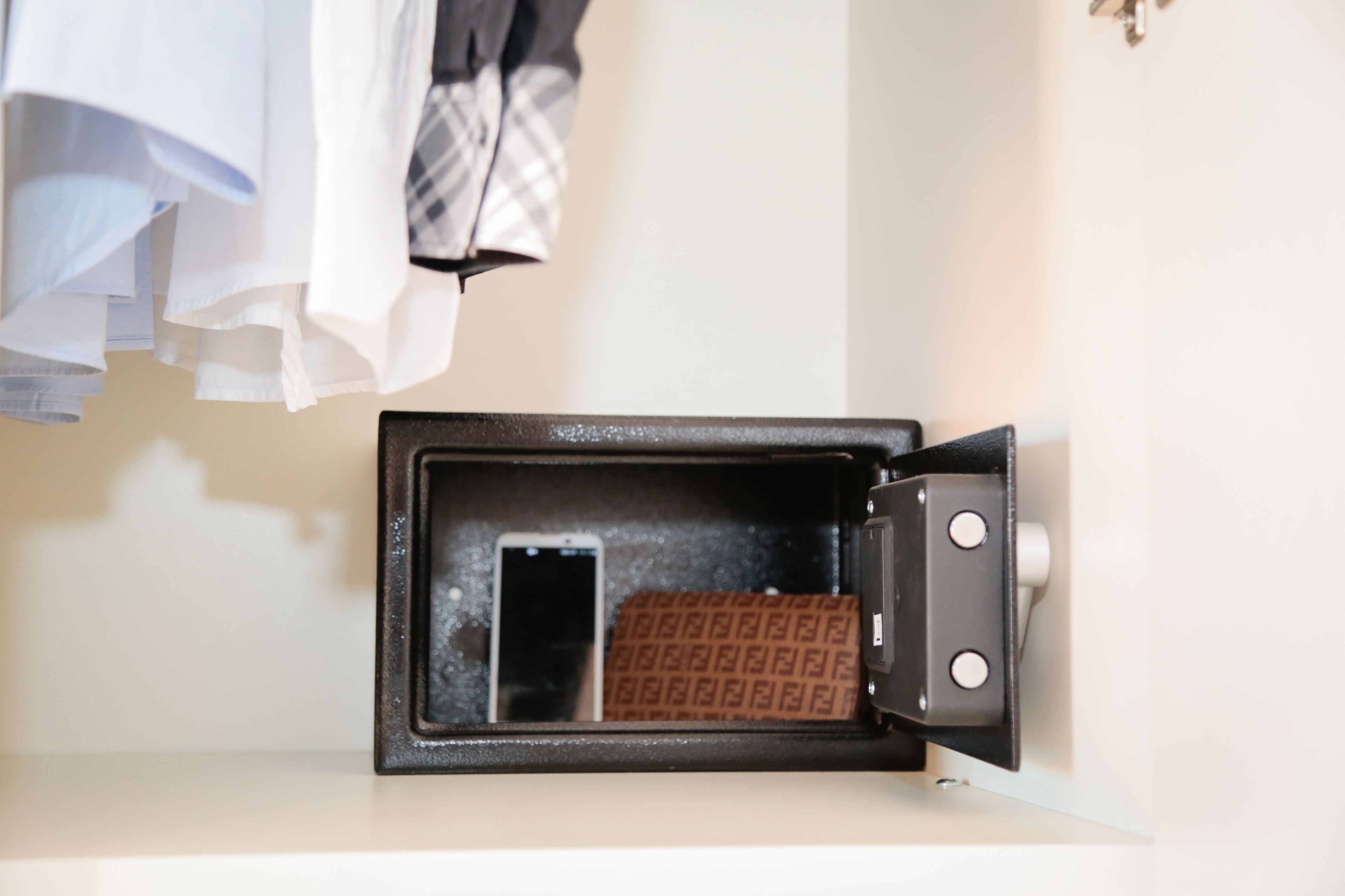 Uma mala com interior estampado, um smartphone e uma trava de metal.