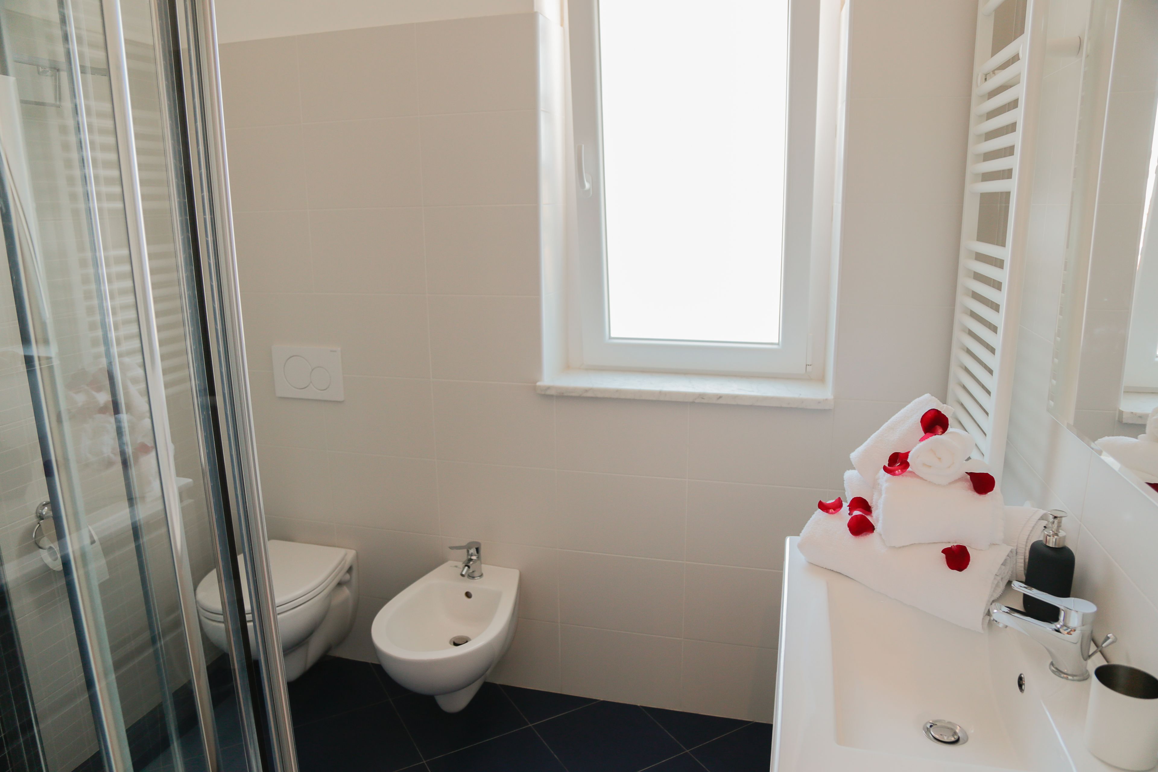 Une salle de bain équipée d’un bidet, de toilettes et d’un lavabo avec un miroir.
