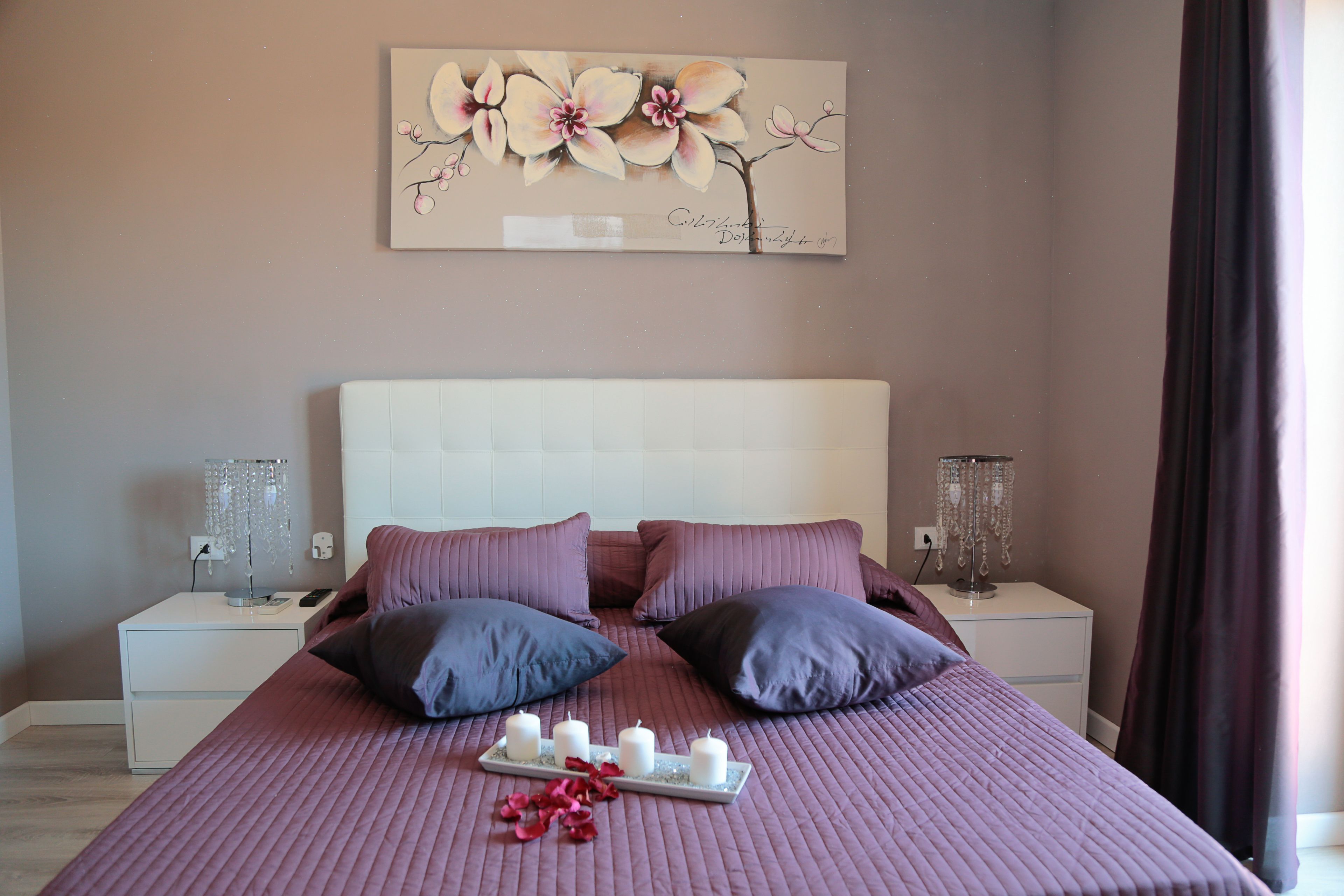 A neatly arranged bedroom with a large bed, two bedside tables, and a wall-mounted artwork.