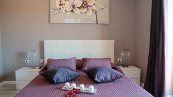 A neatly arranged bedroom with a large bed, two bedside tables, and a wall-mounted artwork.