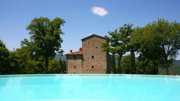 Ein Steinhaus mit einem Pool davor.