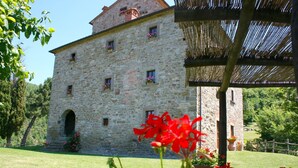 Ein Steinhaus mit vielen Fenstern und einer überdachten Außenfläche.