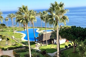 Un resort con una piscina grande, palmeras y vista al océano.
