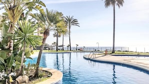 Una piscina con palmeras y vista al océano.