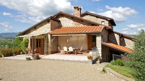 A stone house with a tiled roof, a covered patio with a table and chairs, and a gravel driveway. - Wonderful private villa for 10 people with private pool, WIFI, TV, terrace, pets allowed and par... (Castel San Niccolo)