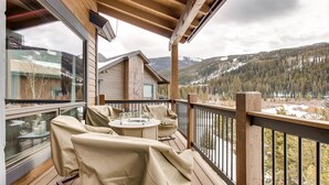 A wooden deck with outdoor seating, a glass door leading to a room, and a view of a mountainous landscape. - River Run Townhomes by Vail Resorts (Keystone)