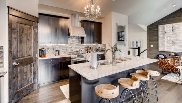 A modern kitchen with a central island, stainless steel appliances, and a chandelier. - River Run Townhomes by Vail Resorts (Keystone)
