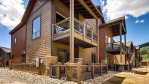 A modern two-story house with a balcony, stone foundation, and a wooden deck. - River Run Townhomes by Vail Resorts (Keystone)