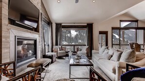 A modern living room with a fireplace, large windows with mountain views, and contemporary furniture. - River Run Townhomes by Vail Resorts (Keystone)