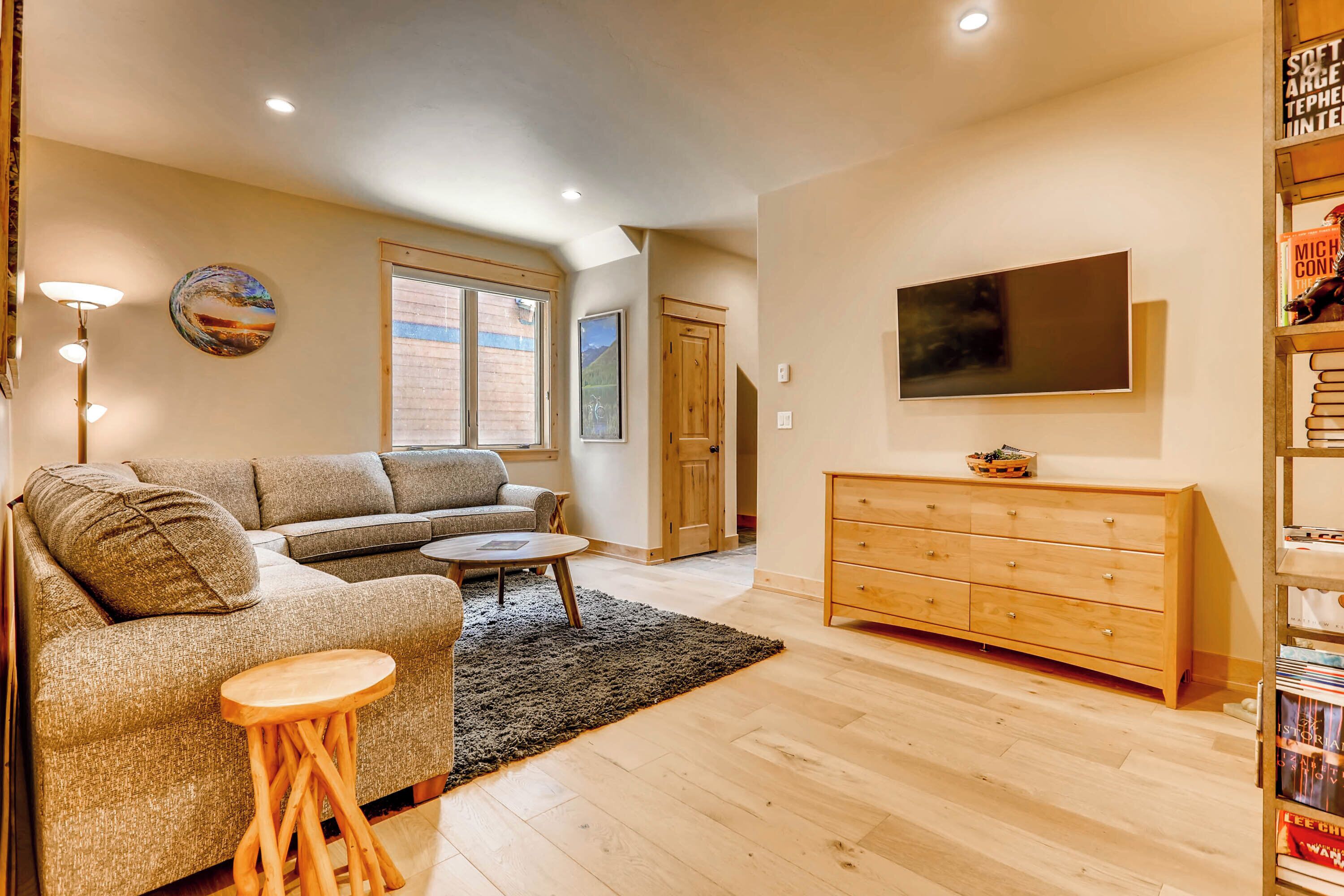 A living room with a sofa, coffee table, and a TV mounted on the wall.