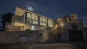 A modern two-story house with a stone facade, large glass windows, and a staircase leading to the upper level. - Marmaras (Lysos)