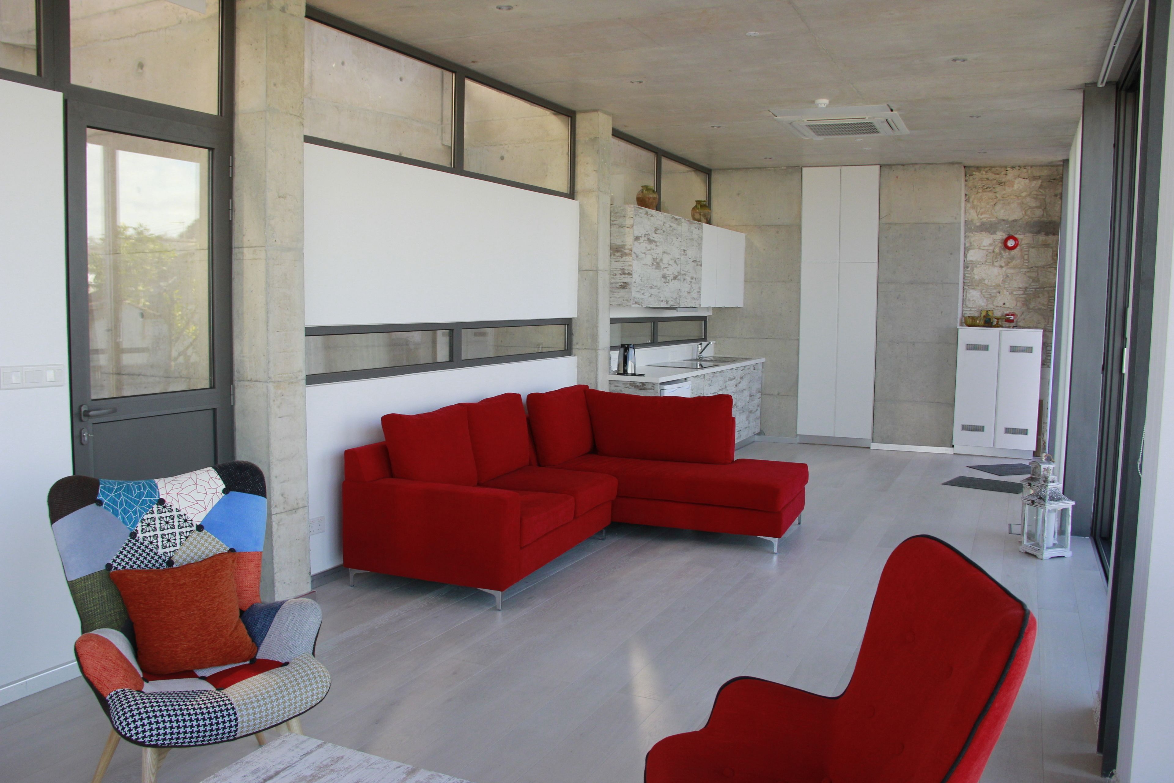 Een moderne woonkamer met een rode modulaire bank, een fauteuil met patroon en een rode fauteuil.