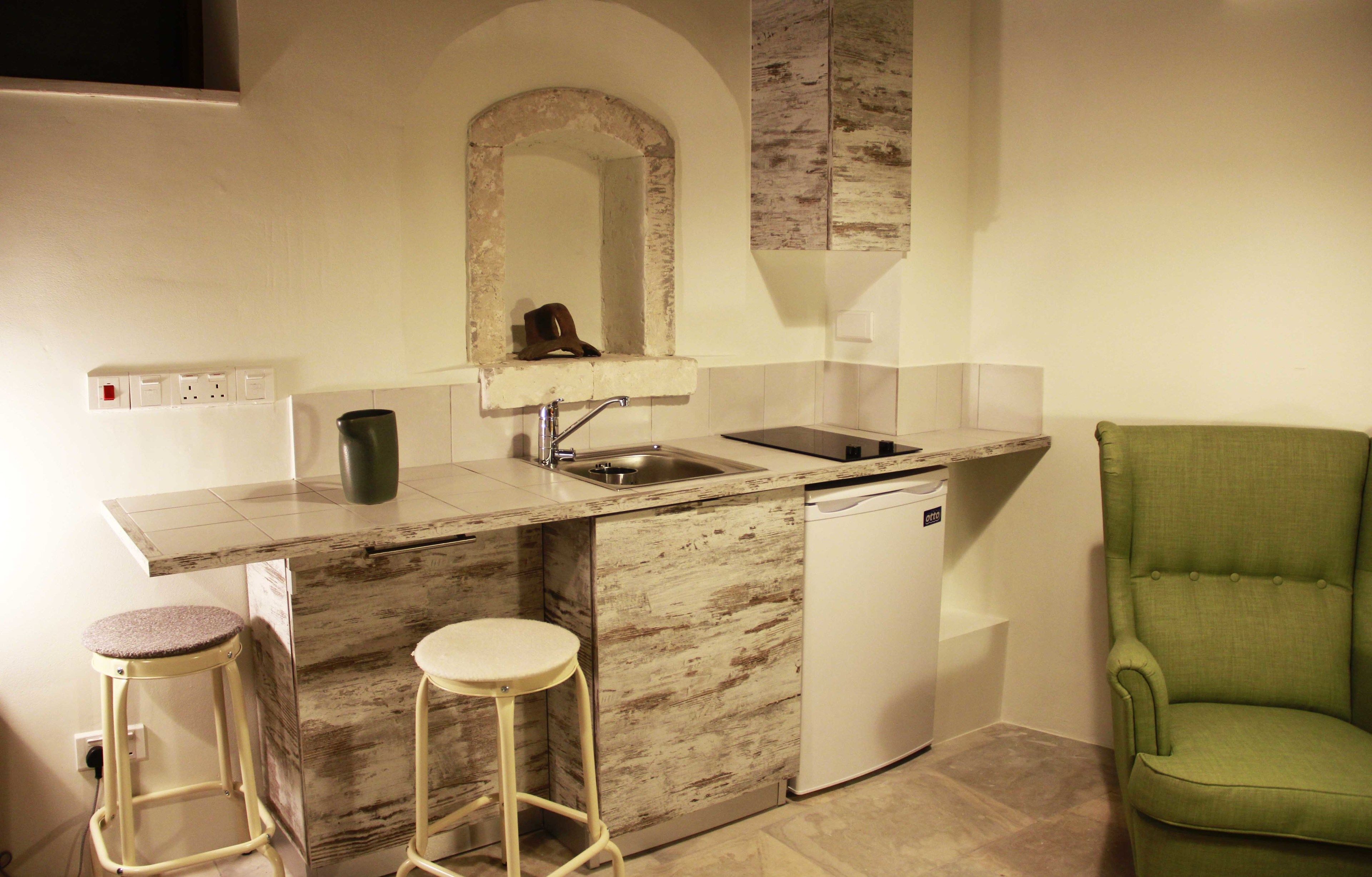 Cozinha compacta com bancada de mármore, máquina de lavar louça embutida e dois banquetes.