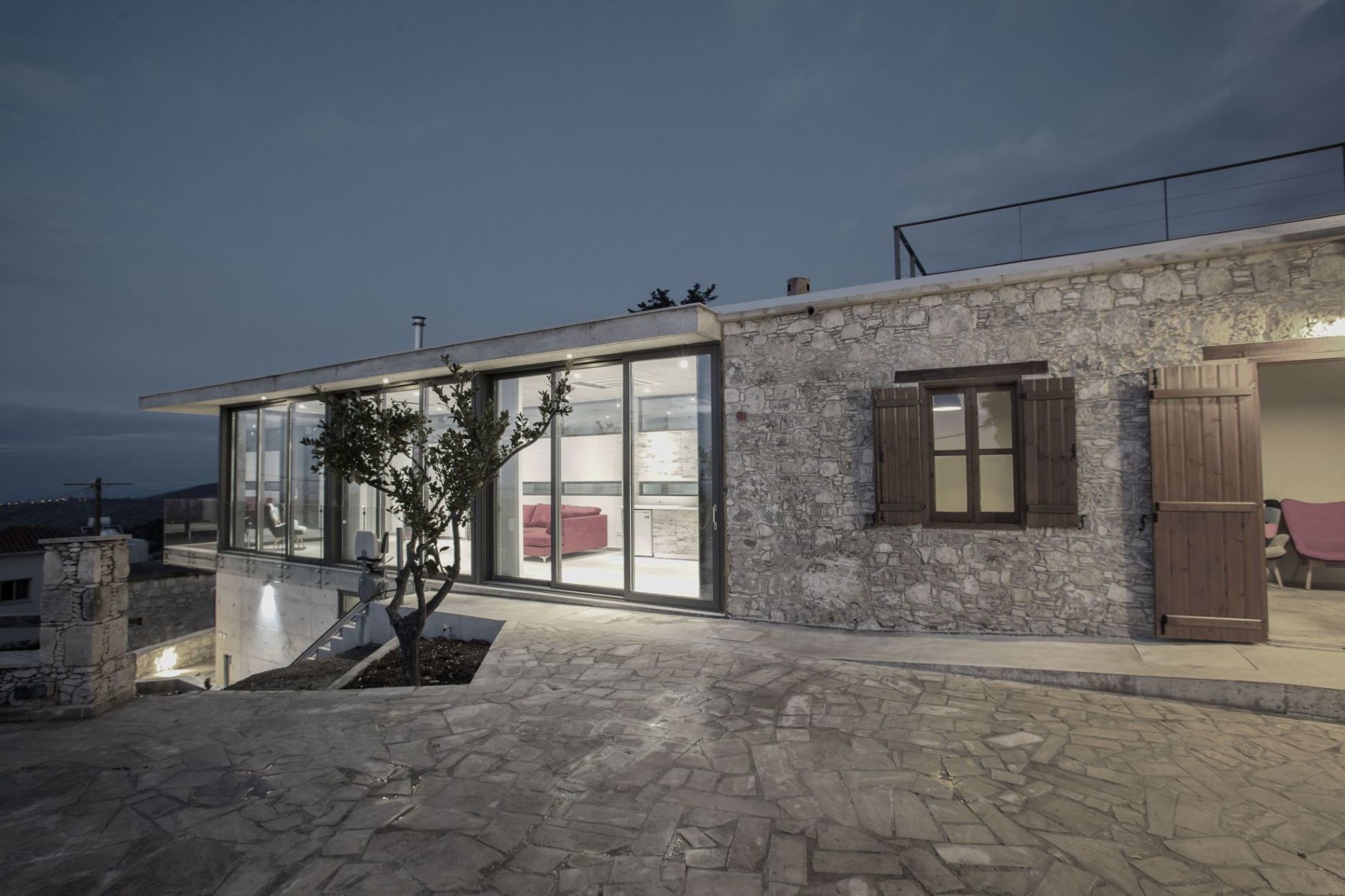 A modern building with a stone facade, large glass windows, and a stone staircase leading to an upper level.