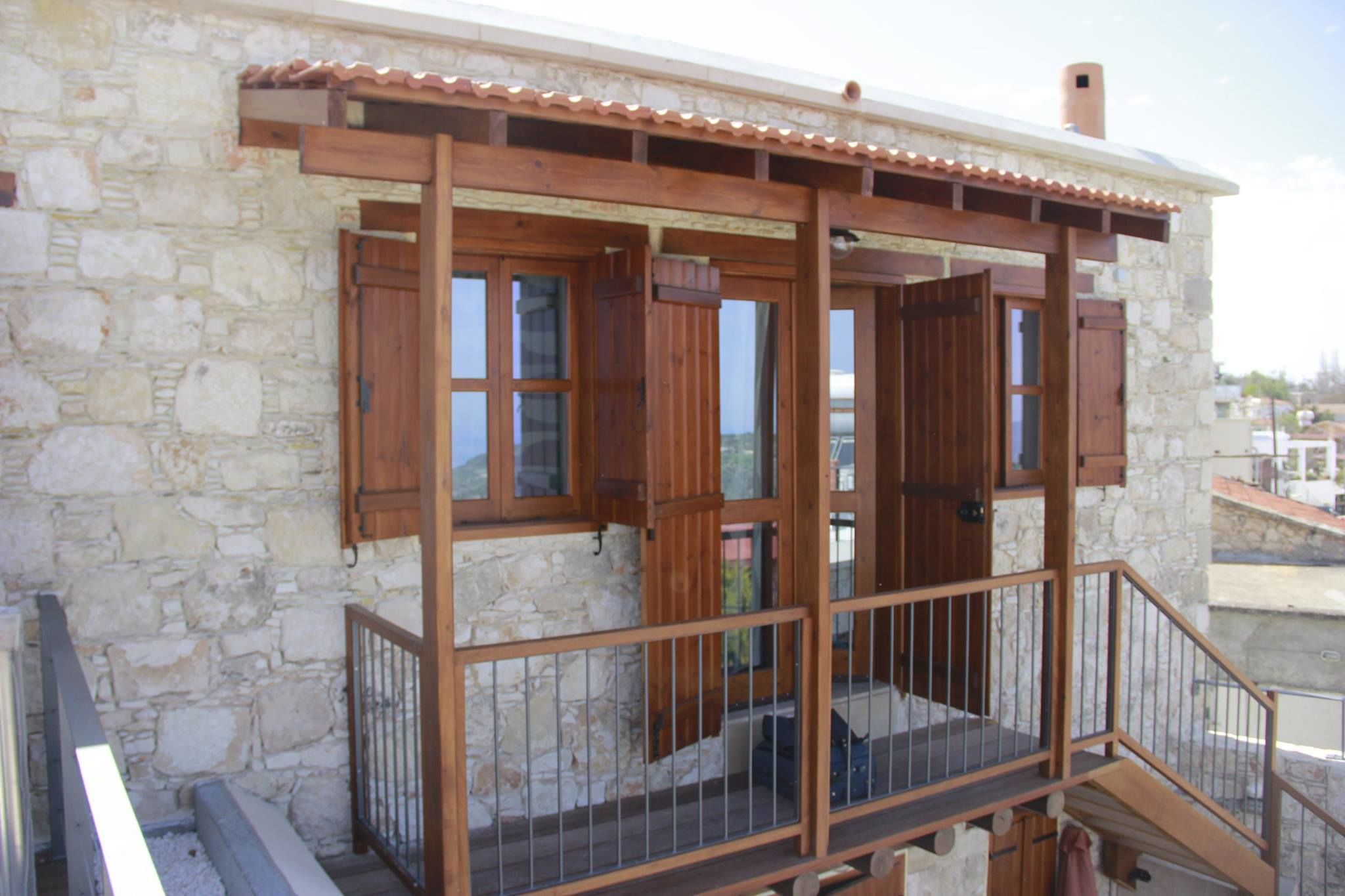 Ein Steinhaus mit einem hölzernen Balkon und einem Metallgeländer.