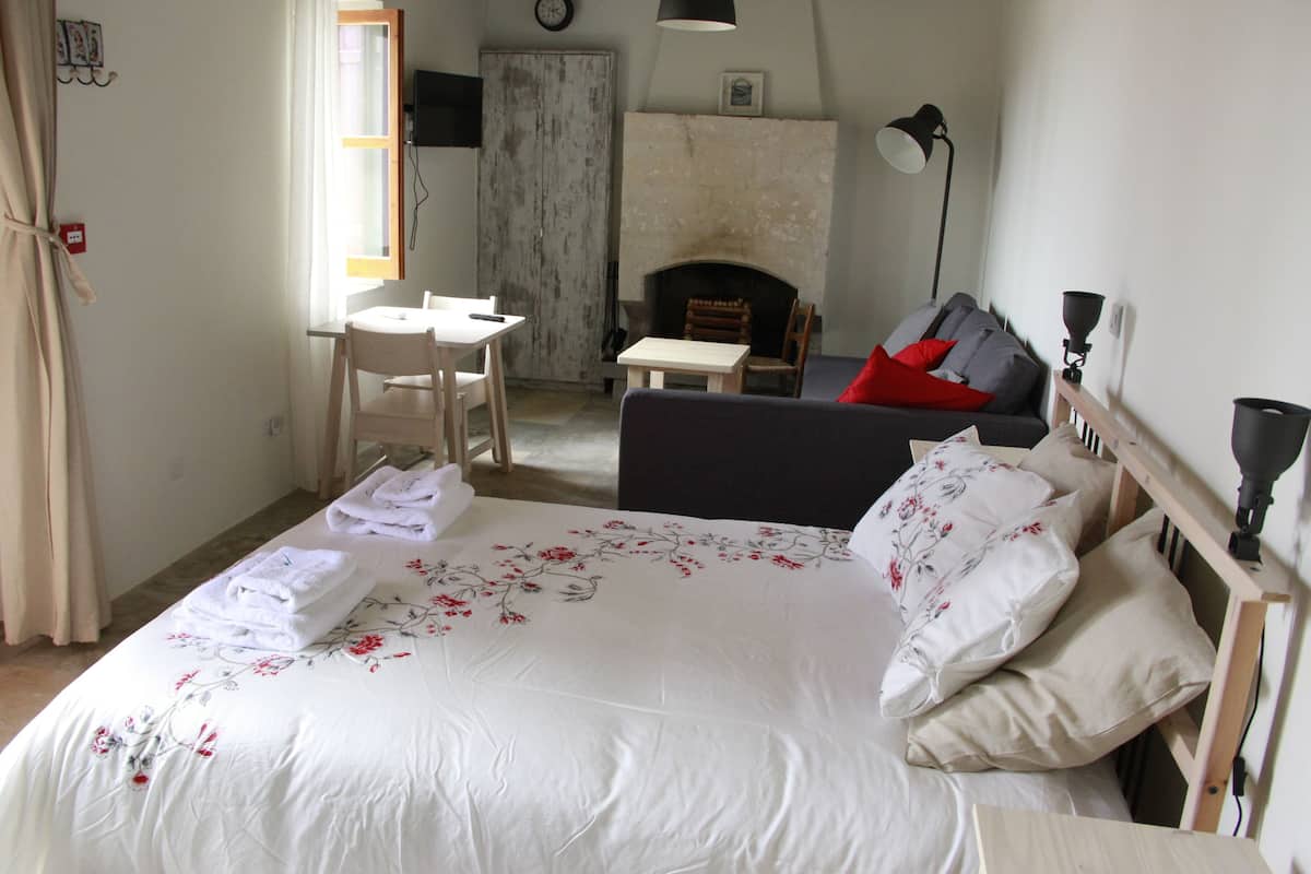 Um quarto com cama, sofá, mesa e lareira.