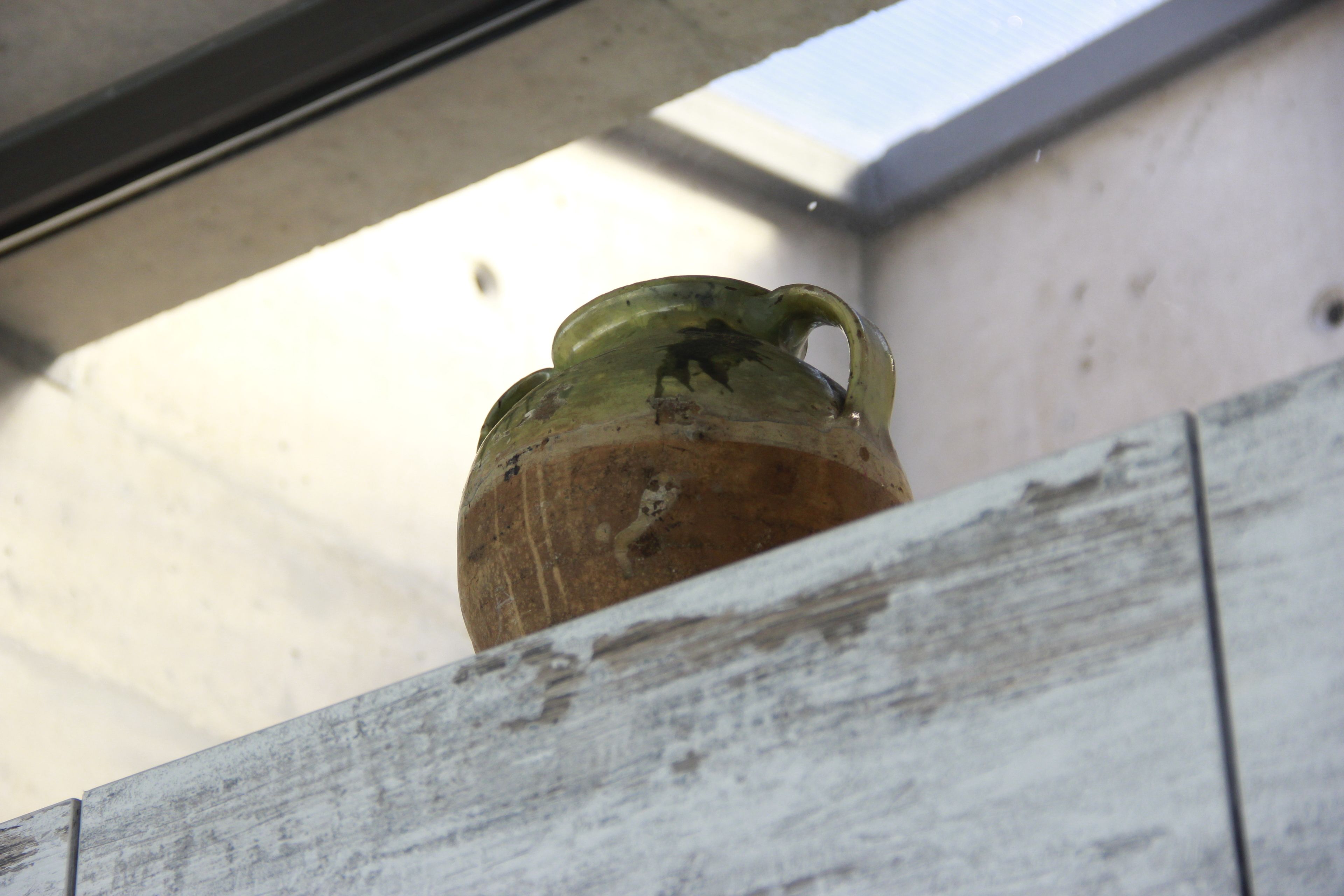 Una struttura in legno rustica con un vaso di ceramica verde.