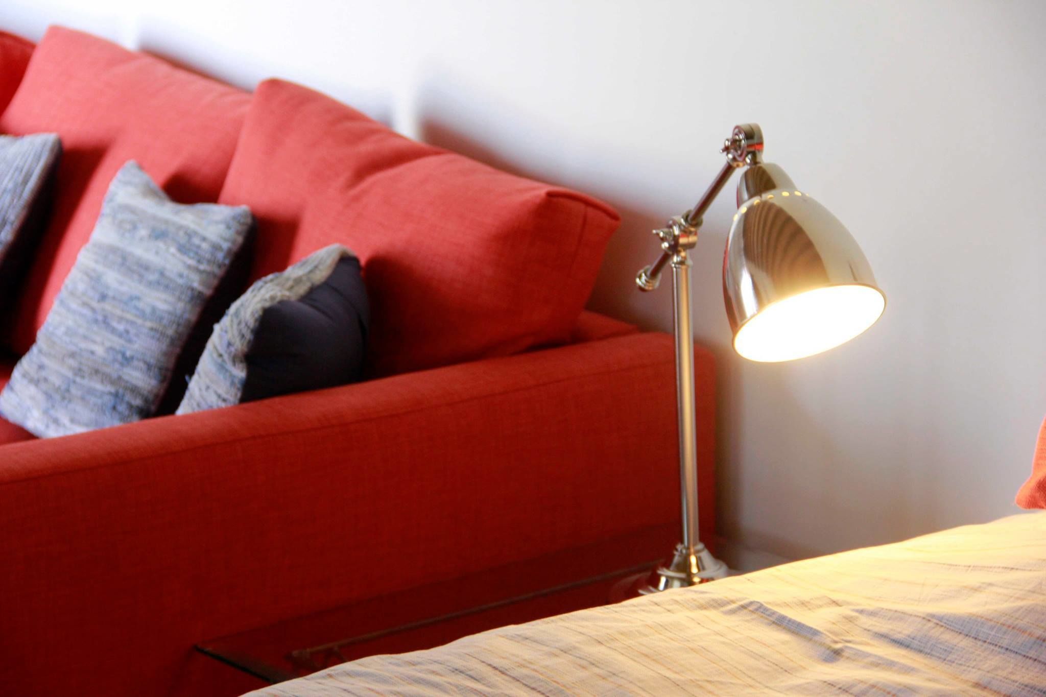 Un divano rosso con cuscini decorati e una lampada da terra.