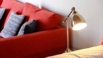 Un divano rosso con cuscini decorati e una lampada da terra.