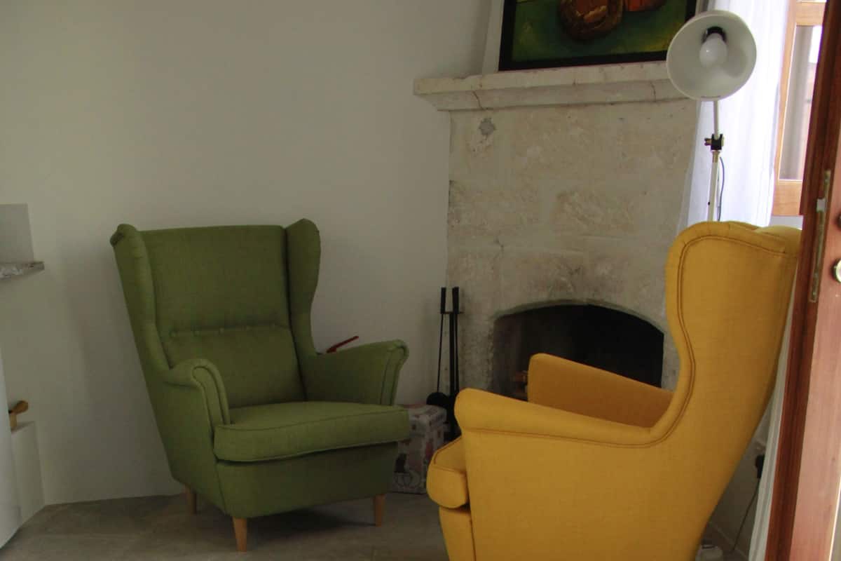 Um quarto com uma poltrona verde, uma poltrona amarela e uma banheira branca com toalhas.